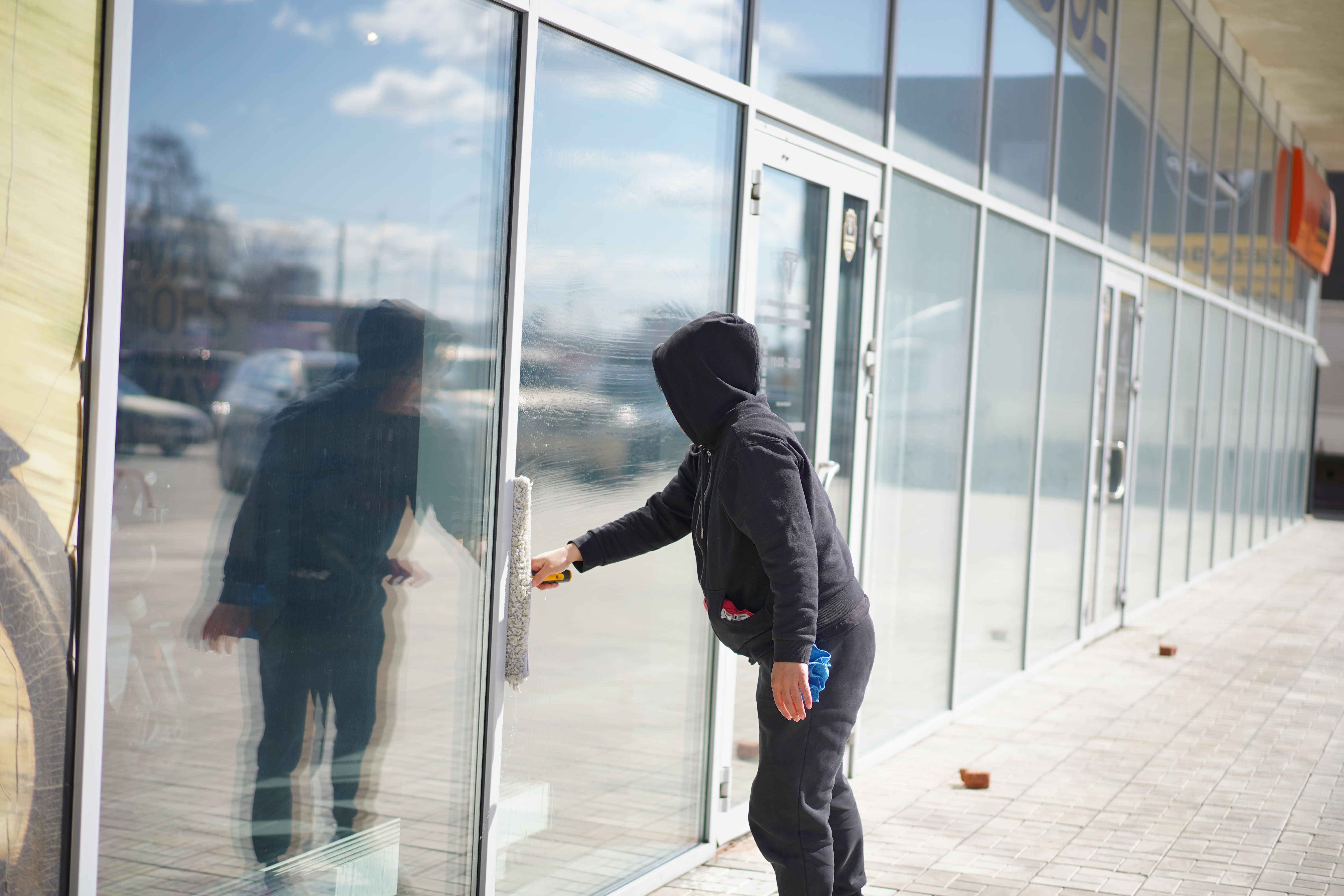 Клинер моет стеклянные окна и двери здания снаружи